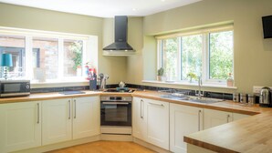 Een moderne keuken met witte kastjes, een zwarte afzuigkap en een raam met uitzicht op groen.
