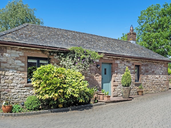 A stone building with a tiled roof, a door, and a chimney.