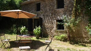 An outdoor patio with a table and chairs, a large umbrella, and potted plants. - OVERHANGING A RIVER, SHEPHERD'S HOUSE, AUTHENTIC, FAMILY-FRIENDLY, WIFI (Pieusse)