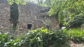 A stone building with a window and a hanging chair outside. - OVERHANGING A RIVER, SHEPHERD'S HOUSE, AUTHENTIC, FAMILY-FRIENDLY, WIFI (Pieusse)