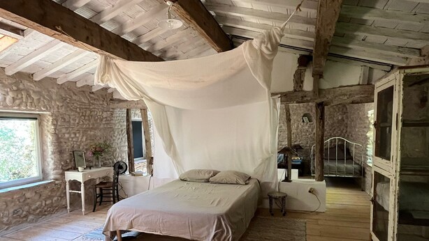 A rustic bedroom with a bed, a desk, and a stone wall. - OVERHANGING A RIVER, SHEPHERD'S HOUSE, AUTHENTIC, FAMILY-FRIENDLY, WIFI (Pieusse)