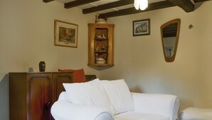 Quarto com um sofá branco revestido, um armário de madeira e um espelho na parede.