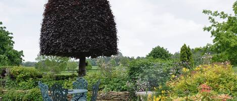 A garden with a unique tree, a stone wall, and a table with chairs.