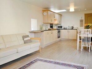 Une cuisine moderne avec des meubles en bois, un plan de travail blanc et un coin repas comprenant une table et des chaises blanches.