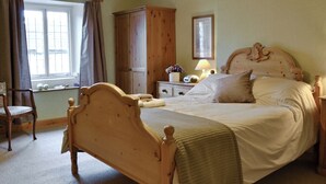 Un dormitorio con cama de madera, una mesita de noche, una silla, un armario, una ventana con cortinas y una lámpara.