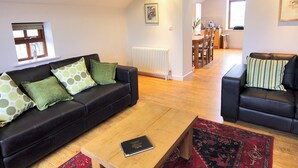 Een moderne woonkamer met een zwarte leren bank, een houten salontafel en een kamerbreed tapijt met een patroon.