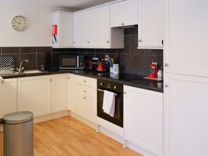 A modern kitchen with white cabinets, a microwave, a kettle, and a sink. - 1 bedroom accommodation in Rispond, near Durness (Rispond, near Durness)
