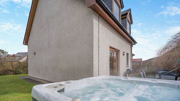 Een hottub in een achtertuin, met een huis op de achtergrond.