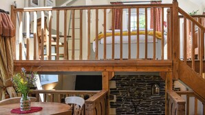 A rustic room with a wooden staircase, a stone fireplace, and a bed with a yellow blanket. - 2 bedroom accommodation in Polbrock, Washaway (Polbrock, Washaway)
