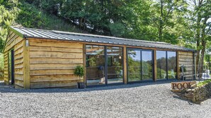 A wooden cabin with large glass doors and a gravel driveway. - 2 bedroom accommodation in Polbrock, Washaway (Polbrock, Washaway)