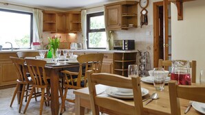 Une cuisine avec des meubles en bois, une table à manger pour quatre personnes et une fenêtre laissant entrer la lumière naturelle.