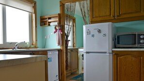 Una cocina con armarios de madera, un refrigerador blanco, un microondas y un lavavajillas.