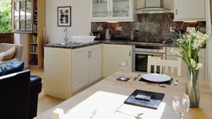 A modern kitchen with a dining area, featuring a skylight, granite countertops, and a dining table set for two. - 1 bedroom accommodation in Capelulo, near Conwy (Capelulo, near Conwy)