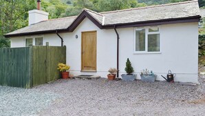 A single-story house with a sloped roof, a wooden door, and a small front porch. - 1 bedroom accommodation in Capelulo, near Conwy (Capelulo, near Conwy)