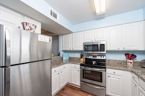 Fully equipped kitchen with refrigerator, oven, microwave, and granite countertop.