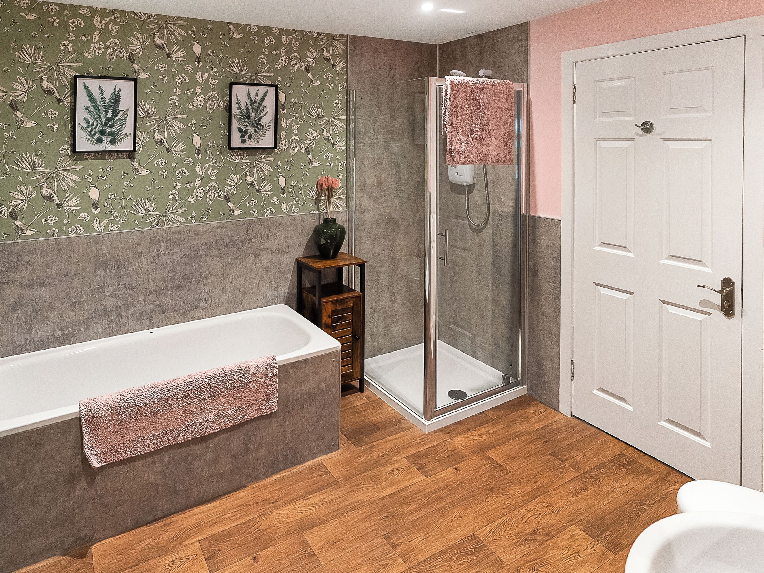 A bathroom with a bathtub, shower, and a door.
