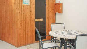 A wooden cabinet with a glass door, a small wooden cabinet above it, and a round table with chairs.