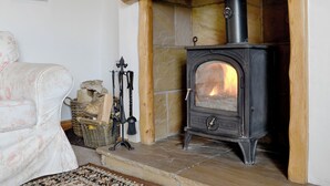 Ein gemütlicher Raum mit einem Steinkamin, einem rustikalen Holzbalken und einem Sofa im Vintage-Stil.