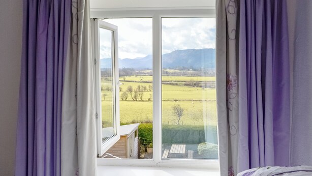 Ein Schlafzimmer mit großem Fenster, einem Bett und violetten Vorhängen.