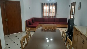 Un comedor con una mesa y sillas de madera, un sofá rojo y una televisión.
