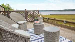 A deck with wicker furniture, a table with a bottle and glasses, and a view of a lake. - 3 bedroom accommodation in Yarrow Moor, near Bellingham (Yarrow Moor, near Bellingham)