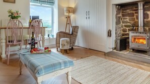 A cozy living room with a stone fireplace, wooden beams, a dining area with a table set for two, and a view through a window. - 3 bedroom accommodation in Yarrow Moor, near Bellingham (Yarrow Moor, near Bellingham)