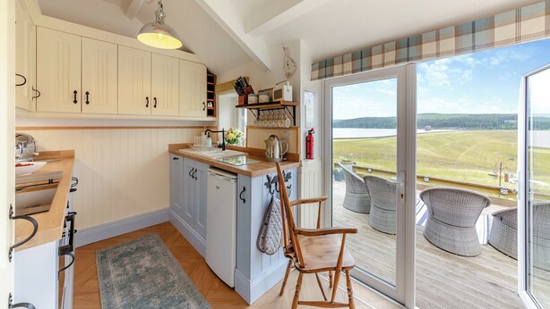 A kitchen with wooden cabinets, a sink, and a view of a balcony with outdoor furniture. - 3 bedroom accommodation in Yarrow Moor, near Bellingham (Yarrow Moor, near Bellingham)