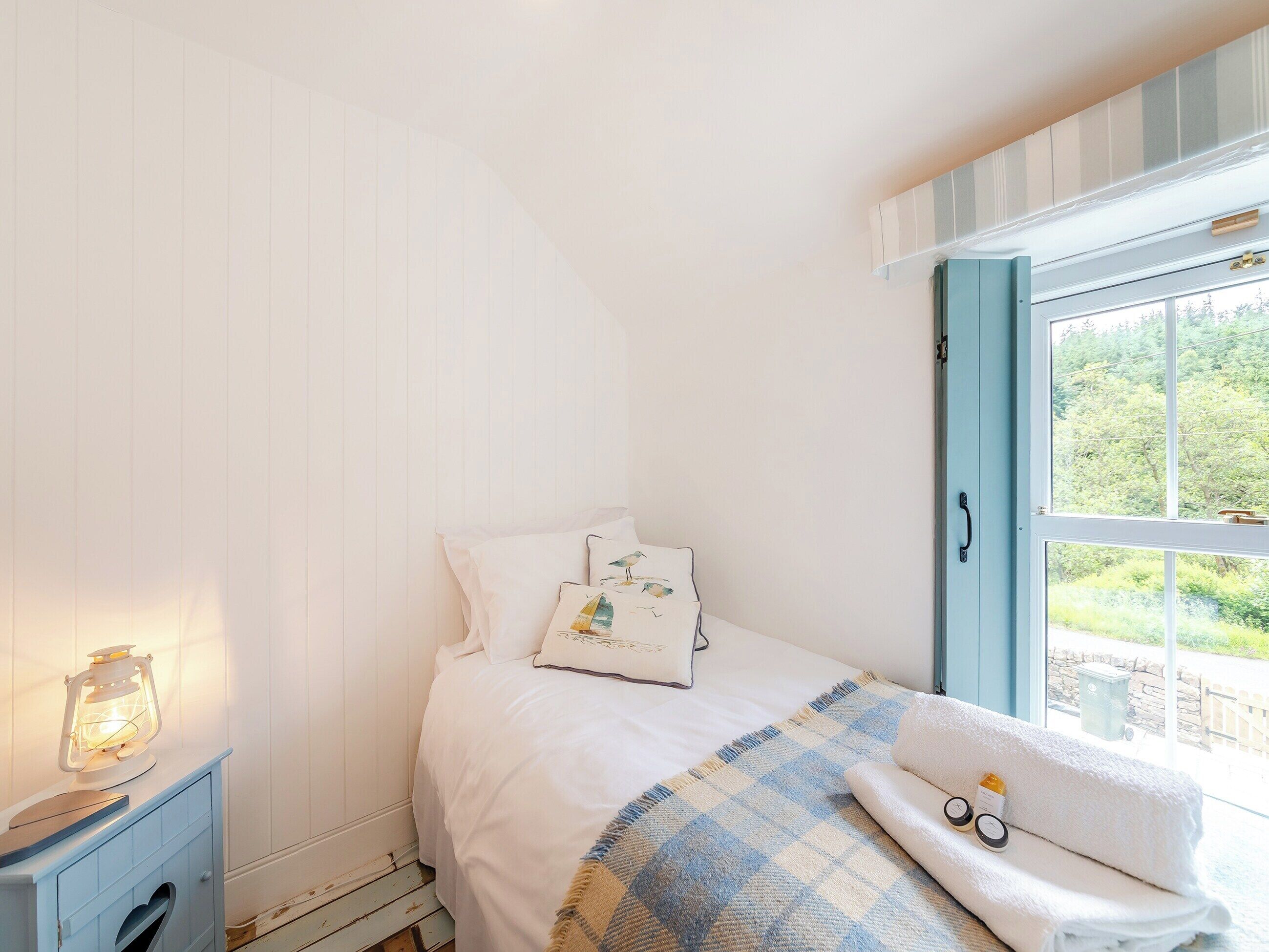 A bedroom with a bed, a nightstand, a window with a view, and a checkered throw blanket.