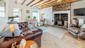 A cozy living room with a stone fireplace, leather sofas, wooden beams, and a television. - 3 bedroom accommodation in Yarrow Moor, near Bellingham (Yarrow Moor, near Bellingham)