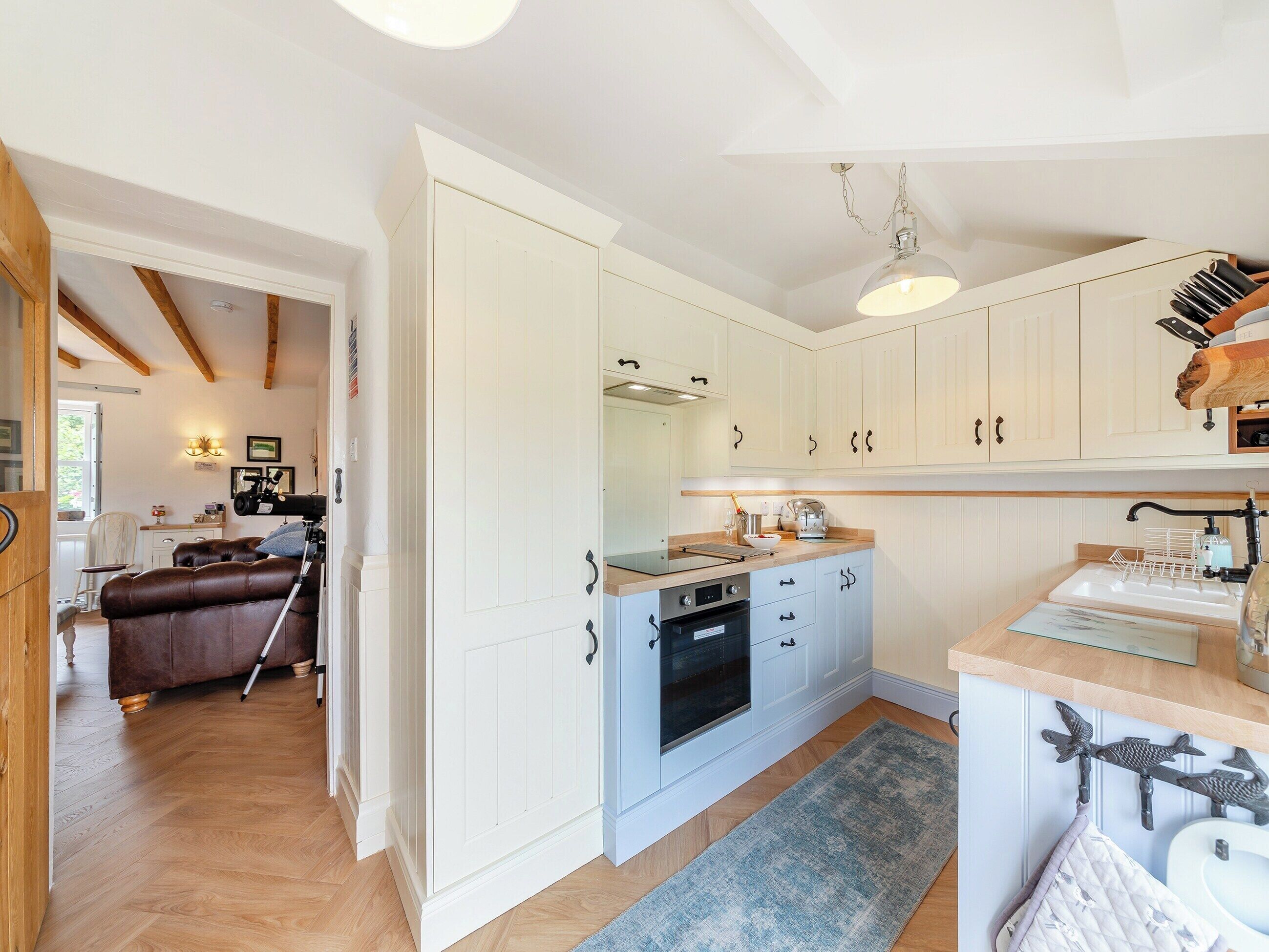 A modern kitchen with white cabinetry, a built-in oven, and a wooden countertop.