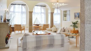 A spacious living room with a white sofa, wooden chairs, a glass coffee table, and a fireplace. - 2 bedroom accommodation in Tehidy Park, near Camborne (Tehidy Park, near Camborne)