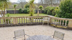 An outdoor patio with a round table and two chairs, surrounded by a stone balustrade and various plants. - 2 bedroom accommodation in Tehidy Park, near Camborne (Tehidy Park, near Camborne)