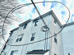 Un edificio de varios pisos con fachada simétrica, numerosas ventanas y líneas de servicios visibles.