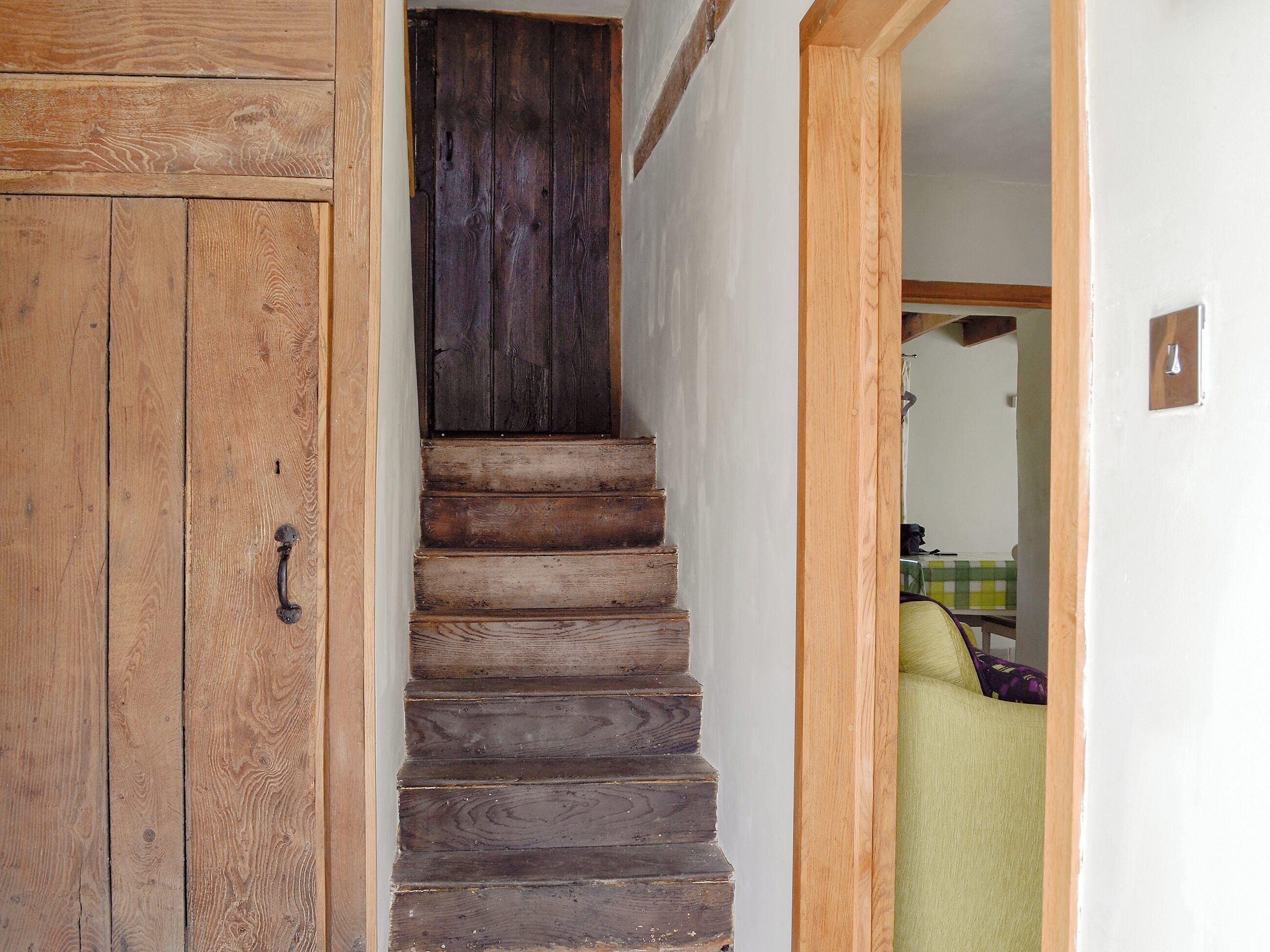 Eine Holztreppe führt zu einem Raum mit einem grünen Sofa.