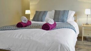 A neatly made bed with white and blue checkered bedding, two pillows, and two rolled towels in red and white. - 3 bedroom accommodation in Llandybie, near Llandeilo (Llandybie, near Llandeilo)