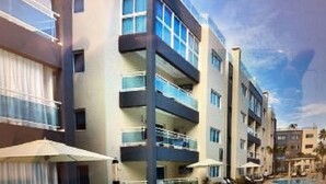 A modern hotel with a swimming pool, multiple balconies, and outdoor seating areas. - Beautiful Punta Cana Beach Escape! (El Cortecito)