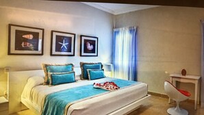 A bedroom with a bed, a nightstand, a chair, and three framed pictures on the wall. - Beautiful Punta Cana Beach Escape! (El Cortecito)