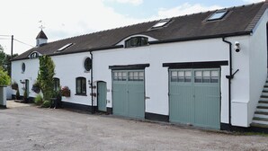A white building with green doors and a sloped roof. - Wee Bridge Farm Cottage (Mobberley, near Knutsford)