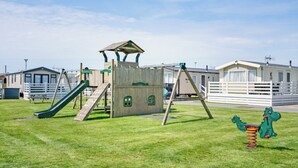 Ein Spielplatz mit Rutsche, Schaukeln und einer Kletterkonstruktion.