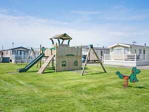 Un parque infantil con tobogán, columpios y estructura para escalar.