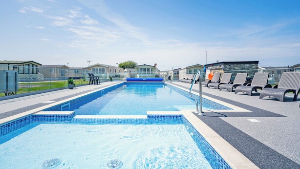 Ein Schwimmbecken mit Liegestühlen und blauem Himmel.