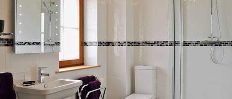 Een moderne badkamer met een douchecabine van glas, een wit toilet en een wastafel met spiegel.