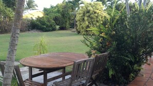 Un patio al aire libre con una mesa redonda de madera y cuatro sillas.