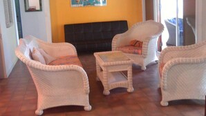 Una sala con muebles de mimbre, un sofá oscuro y un mapa mural.