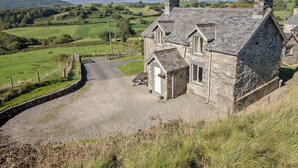 A stone house with a gravel driveway and a stone wall.
