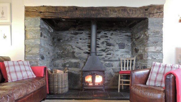 A cozy living room with a stone fireplace, leather sofas, and a woven basket.
