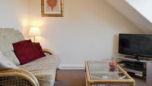 A cozy living room with a sofa, a glass coffee table, a television, and a framed picture on the wall. - 1 bedroom accommodation in Keswick (Keswick)