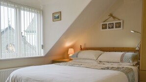 A bedroom with a large bed, a nightstand with a lamp, a window with blinds, and a picture on the wall. - 1 bedroom accommodation in Keswick (Keswick)