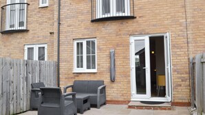 Een stenen huis met balkon, een schuifpui en tuinmeubilair.