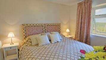 Une chambre à coucher avec une couvre-lit à motifs, deux lampes de chevet, une table de chevet et une fenêtre avec des rideaux.